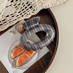 Detail of grey glossy oval hair claw clip featuring France Handmade text on wooden tray
