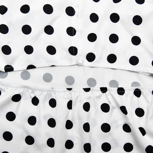 Macro detail of satin polka dot dress with hollow-out design and pearl button