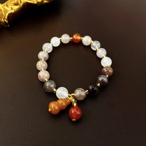 Detailed shot of ceramic beaded bracelet featuring an orange gourd charm on leather