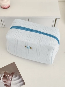 Close-up of light blue knitted makeup bag with rose detail and zipper texture