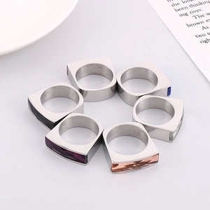 Group of stainless steel gold rings with colorful rectangular crystal stones on a white tray