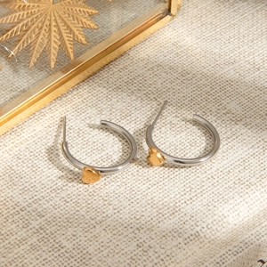 Minimalistische Edelstahl-Creolen in Silber und Gold mit Herzanhänger auf Stoff