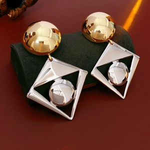 Macro shot of geometric two-tone metal earrings with gold studs and silver diamond frames