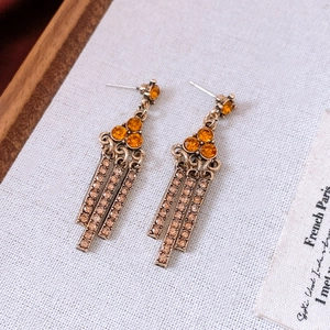 Detail of vintage bronze triangular earrings with amber rhinestones and long tassels