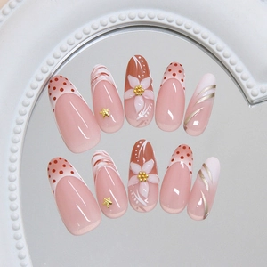 Handmade oval press-on nails with pink base, red dots, floral patterns and gold stars
