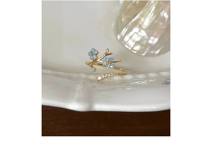 Macro detail of S925 silver flower ring with blue enamel and crystal accents on ceramic tray