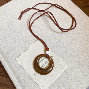 Retro round resin and wood bead pendant necklace with brown cord on a vintage book