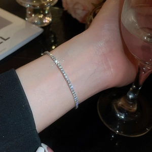 Detailed view of shimmering silver tennis bracelet worn on wrist with luxury party vibe