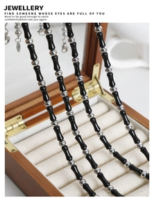 Close-up of black bamboo-shaped agate beads and silver accents on beaded necklaces