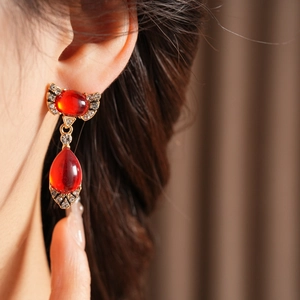 Close-up of vintage style bow earrings with red teardrop gemstones and small diamonds