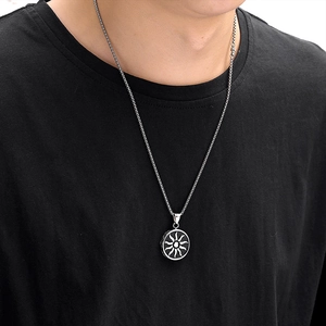 Close-up of a silver sunburst pendant with black background on a male model wearing black