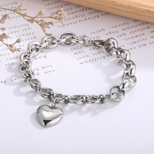 Detailed view of silver heart pendant on chunky steel chain link bracelet setup