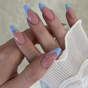 Detail view of almond press-on nails with nude base and light blue french wave tips