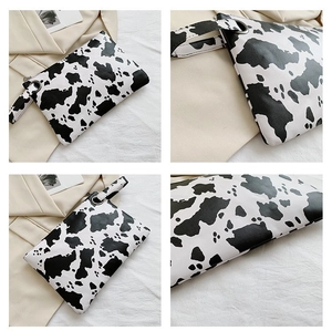 Detail shots of cow print envelope clutch showing wrist strap and metallic ring hardware