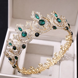Detailed view of vintage gold bridal crown with green emeralds and crystals in a box