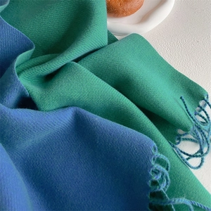 Close-up of dual-tone cashmere-style scarf featuring twill texture and fringed edges