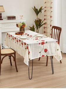 Close-up of white lace tablecloth featuring festive red poinsettia and green leaf embroidery
