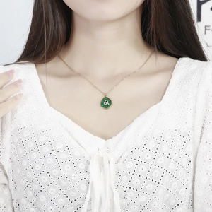 Golden Leo zodiac necklace with green malachite texture pendant worn on a lace top