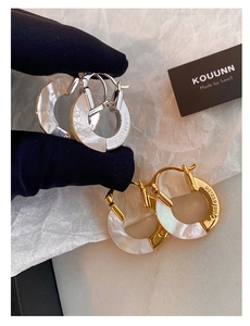 Macro shot of S925 hoop earrings with mother of pearl inlay and engraved text