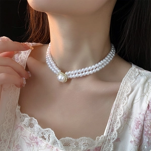 Gros plan d'un collier de perles double épaisseur avec fermoir doré sur le cou