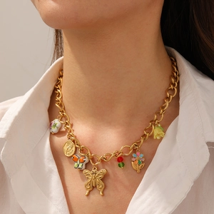 Golden chunky chain necklace with butterfly and flower pendants worn by a model