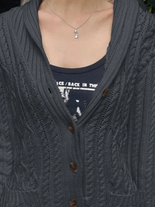 Close-up of dark grey cable knit cardigan featuring button closure and texture