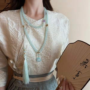 Detail of light blue glass beaded necklace with tassel and safety buckle pendant