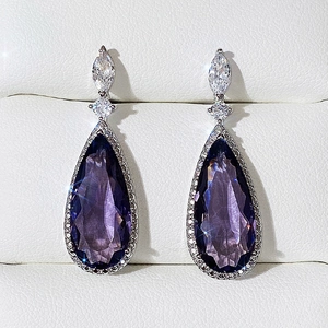 Détail des boucles d'oreilles goutte violette avec cristaux et monture argentée