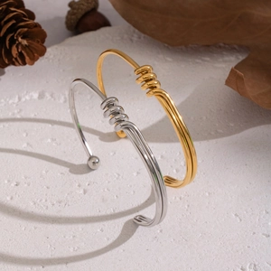 Pair of minimalist 18K gold and silver plated twisted knot open bangles on stone