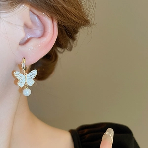 Dettaglio dell'orecchino vintage a farfalla con perla e zircone sull'orecchio