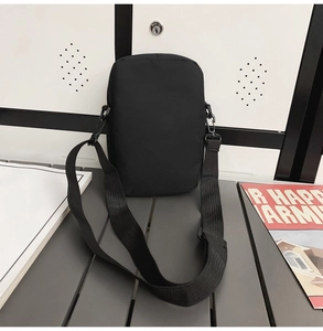 Detail of minimalist black nylon crossbody bag with adjustable wide strap and plastic hook