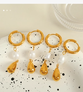Dettaglio di orecchini a cerchio dorati con perle irregolari e pendenti a goccia d'oro