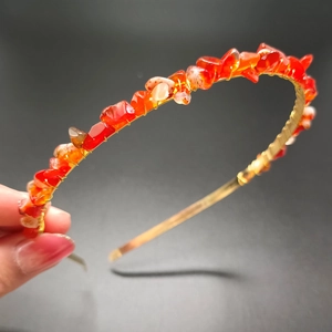 Macro detail of hand-wrapped orange crystal raw stones on a gold metal crown headband