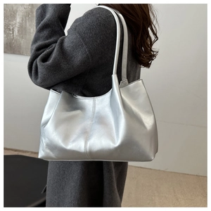 Close-up of metallic silver tote bag with vertical stitching on minimalist shoulder strap