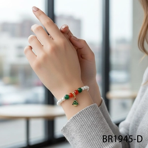 Detail of Christmas pearl bracelet with red and green beads and golden tree charm