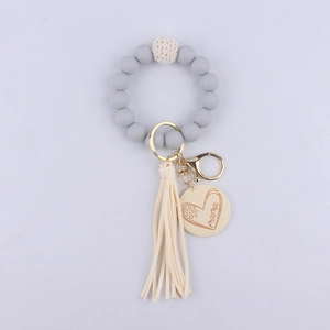 Detail of grey silicone bead keychain with golden Mama charm and beige tassel