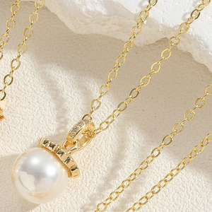 Macro shot of elegant gold chain with large white pearl pendant and zircon crown detail