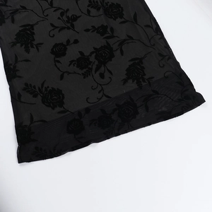 Detail of black flocked rose pattern on sheer mesh fabric for a sexy party dress