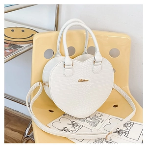 Détail du sac à main cœur blanc à motif crocodile avec garniture dorée et poignées