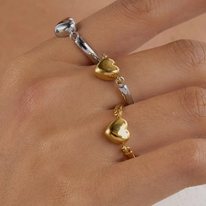 Detailaufnahme von Herz-Anhänger-Ringen in Gold und Silber an einem Model