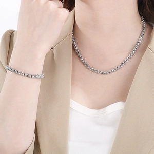 Close-up of geometric stainless steel necklace and bracelet on a beige suit