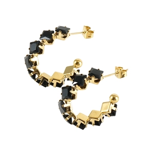 Detail view of gold C-shape hoop earrings featuring inlaid black square-cut gemstones