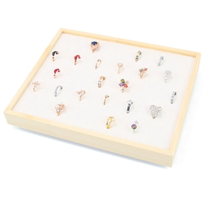 Wooden jewelry tray display with velvet slots showcasing various fashion rings for retail