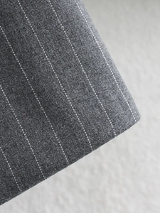 Detailed close-up of dark grey pinstripe woven fabric for suits and skirts