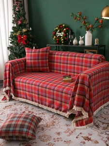 Detail of red plaid sofa throw with white fringe in a festive Christmas living room setting
