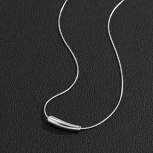 Minimalist silver men's necklace with curved bar pendant on black textured surface