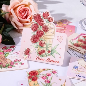 Close-up of pink greeting card featuring rose illustrations and Love Letters text