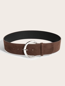 Gros plan sur une large ceinture en daim marron avec boucle ronde en métal argenté