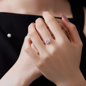 Detail shot of a model wearing a double heart ring with pink and clear gemstones