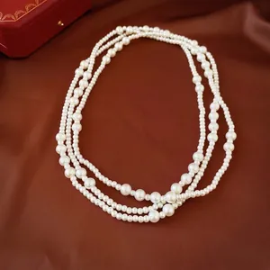 Elegant multi-layer white pearl necklace displayed on luxurious red satin fabric